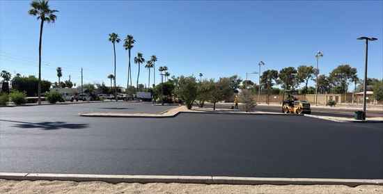 Fresh asphalt paving and roller compaction on a commercial parking lot