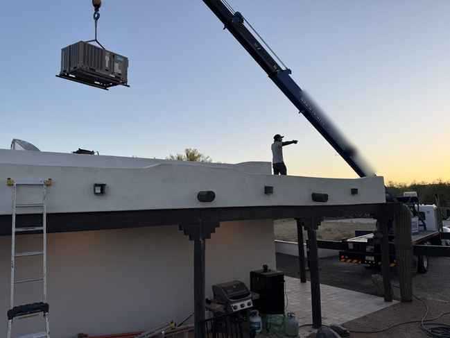 Crane lifting an HVAC unit onto a Southwestern flat-roof home